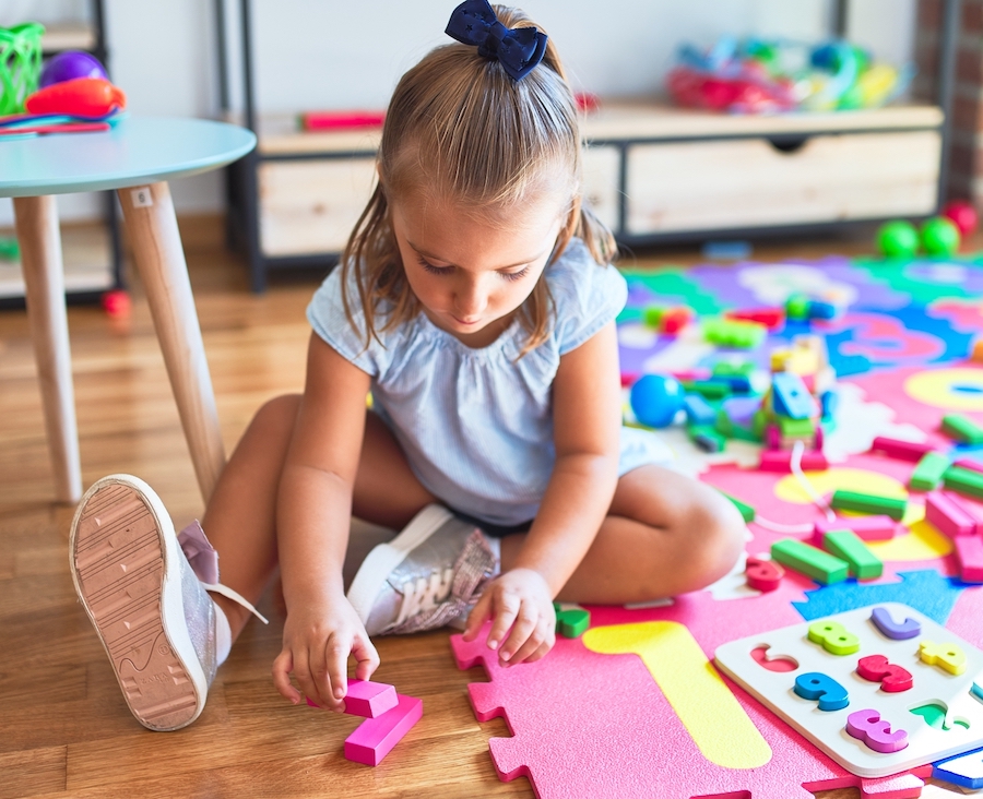 Young beautiful blonde girl kid enjoying play school with toys at kindergarten, smiling happy playing at home