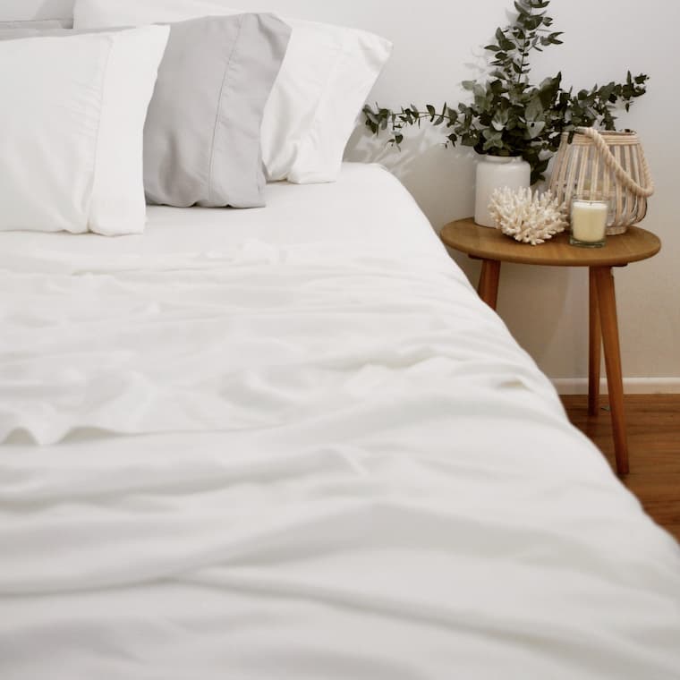 white bamboo sheet set for bedroom with side wood table and decorative candle and flower