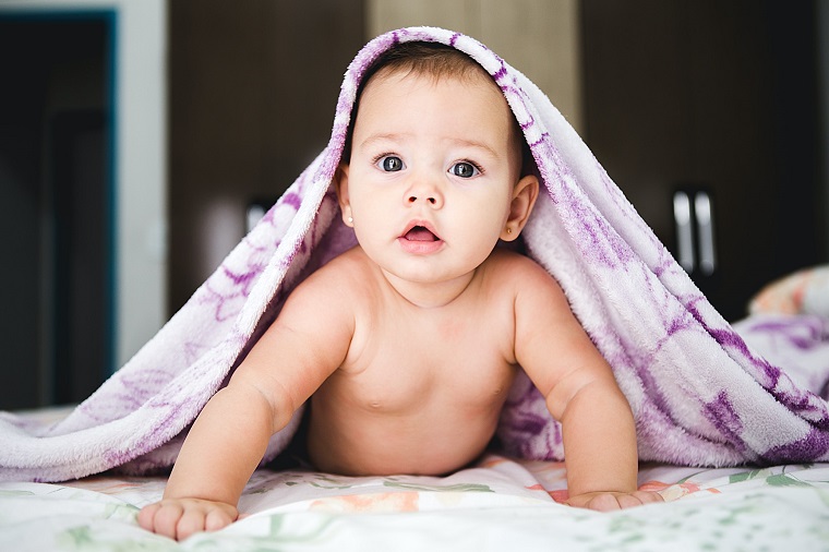 picture of a baby under a purple blanket on a bed