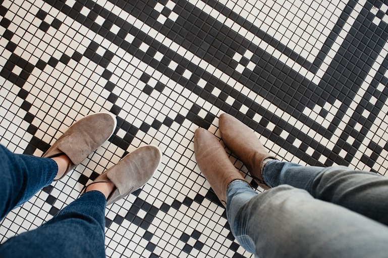 picture of two women legs in jeans and boots on white and black tiles 