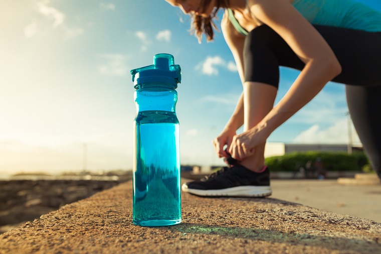 plastic water bottle and woman tying her shoe in the background 