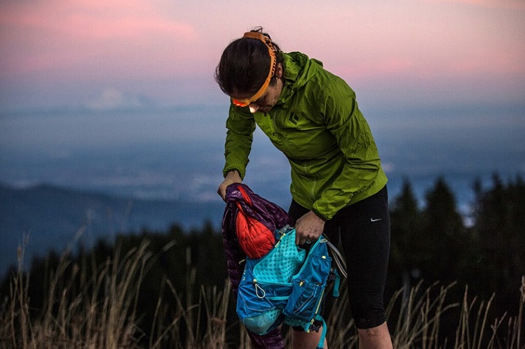 man using headlamp to search through bag