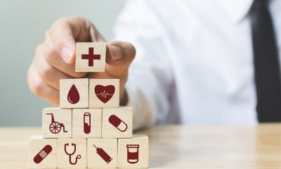 doctor putting a wooden cube with a red cross inrpinted on it on top of a stack of other wooden cubes