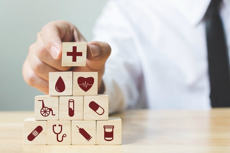 doctor putting a wooden cube with a red cross inrpinted on it on top of a stack of other wooden cubes