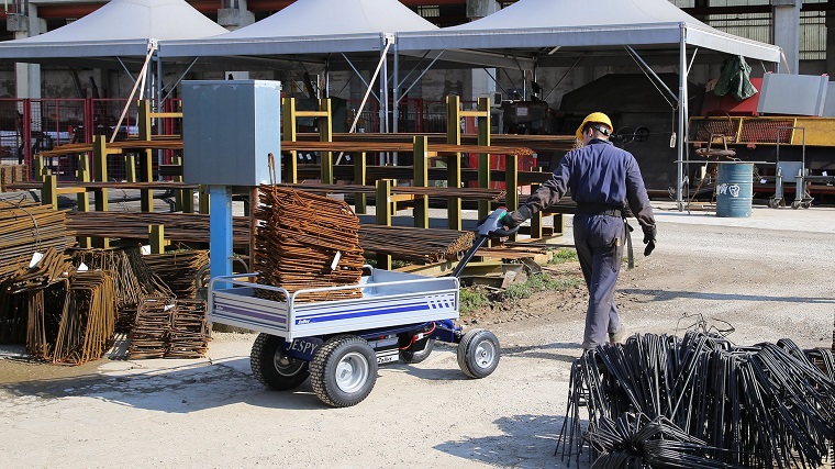 Man pulling battery-powered trolley platform with load