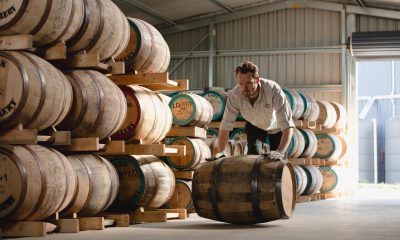 Worker rolling oak whisky barrels in a distillery warehouse