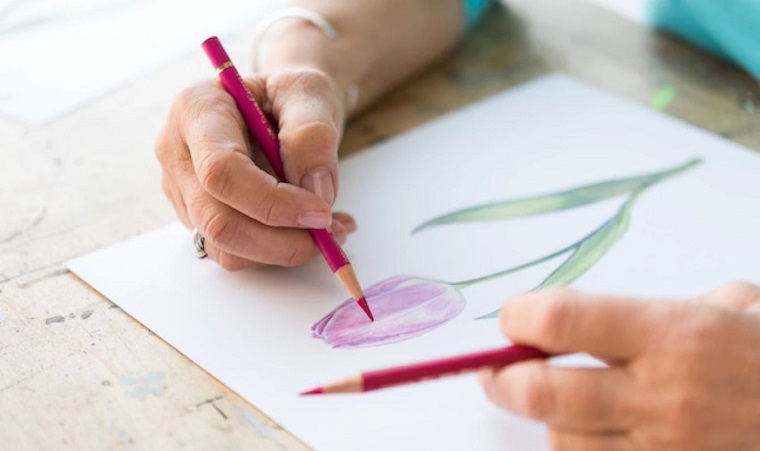 woman painting flower with a pink colored pencil