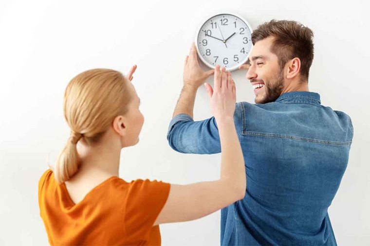 couple placing the analogue clock on the wall