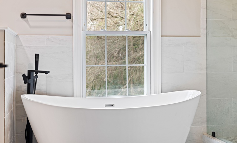 white freestanding bathtub and black faucets